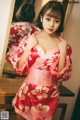 A woman in a red and white kimono posing in front of a mirror.