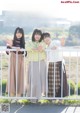 A group of young women standing next to each other near a fence.