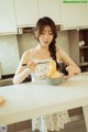 A woman in a white dress holding a bowl of food.