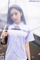 A woman in a white shirt holding an umbrella.