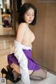 A woman in a purple skirt and black stockings is posing for the camera.