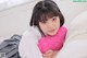 A woman laying on a bed holding a pink heart shaped pillow.