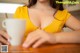 A woman in a yellow dress holding a cup of coffee.