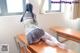 A woman sitting on top of a wooden desk.