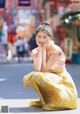 A woman sitting on the ground in a yellow skirt.