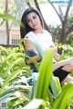 A woman sitting on a rock in the middle of some plants.