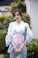 A woman in a blue and white kimono holding an umbrella.