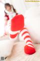 A little girl in a red and white striped outfit laying on a bed.