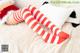 A woman in a santa hat laying on a bed with red and white striped stockings.