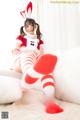 A woman in a red and white outfit sitting on a bed.