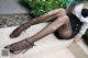 A woman sitting on the steps of a building wearing black stockings.