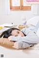 A woman laying on a couch with her head on a pillow.