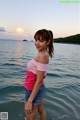 A woman standing in the water at the beach.