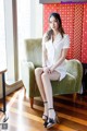 A woman sitting on a green chair in a room.