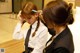 A woman in a white shirt and black tie is getting her hair done.