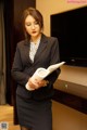 A woman in a business suit holding a book.