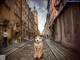 A woman in a bikini sitting on a cobblestone street.