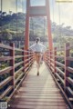 A woman walking across a wooden bridge in a park.