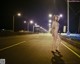 A naked woman standing on the side of a road at night.