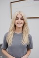 A woman with long blonde hair standing in front of a whiteboard.