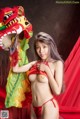 A woman in a red bikini posing with a dragon mask.