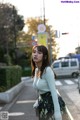 A woman standing on the side of a street next to a traffic light.