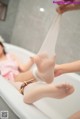 A woman in a bathtub with her feet up in the air.