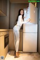 A woman standing in front of a white refrigerator.