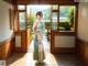 A woman in a kimono standing in front of a window.