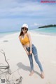 A woman standing on a sandy beach next to the ocean.