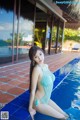 A woman in a blue bikini sitting on the edge of a pool.