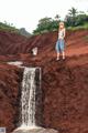 A woman standing on top of a cliff next to a waterfall.