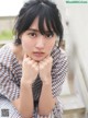 A woman sitting on a bench with her hands on her chin.