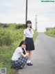 A couple of young women sitting on the side of a road.